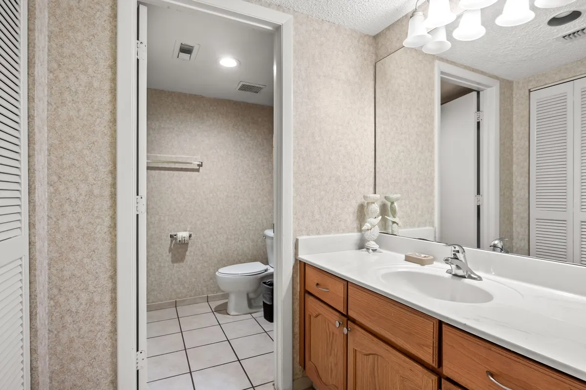 A spacious bathroom with a double sink vanity, expansive mirror, and tidy tilework. The space is well-lit and organized, creating an atmosphere conducive to personal grooming and tranquil self-care routines.
