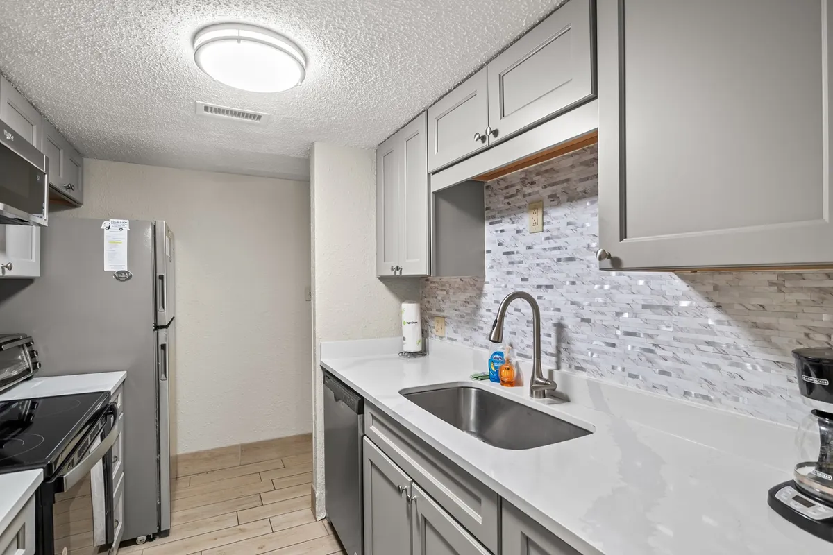 A modern kitchen with sleek cabinetry, a spacious countertop, and a visible kitchen sink. The space is arranged for practical meal prep, and subtle cues like utensils and dishware suggest an environment ready for family cooking or gatherings. The atmosphere is functional and contemporary, ideal for those who want to prepare home-style meals.