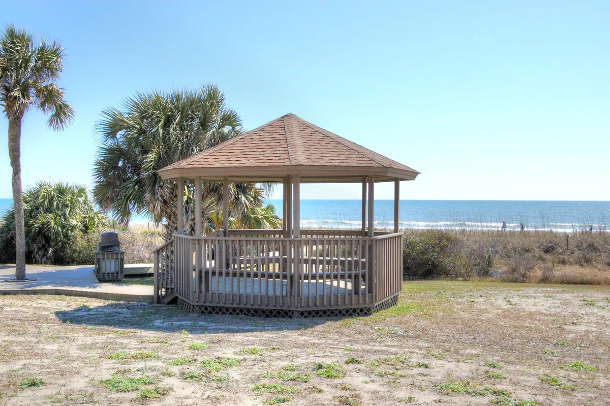 A charming gazebo surrounded by palm trees, overlooking the ocean—a perfect spot for relaxing, picnicking, or soaking up coastal breezes.