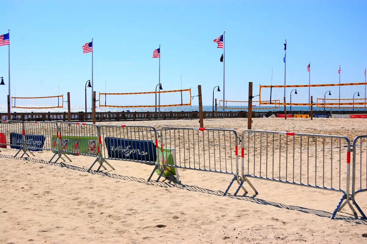This image captures a lively stretch of beach, featuring volleyball nets, American flags, and beach barriers. The scene hints at both community activity and opportunities for tranquil walks along the shoreline. The wide sandy expanse and open sky evoke the refreshing, uncrowded ambiance typical of Myrtle Beach in the winter months.