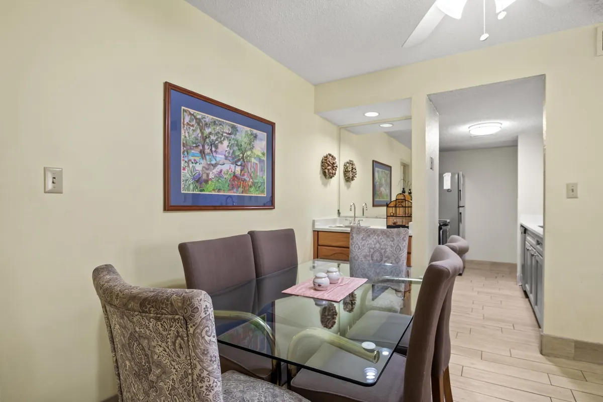 A stylish dining area featuring a dining table set for a meal, artwork adorning the walls, and a glimpse of the adjoining kitchen. The space is designed for comfort and social connection, with ample seating for family breakfasts or cozy dinners.